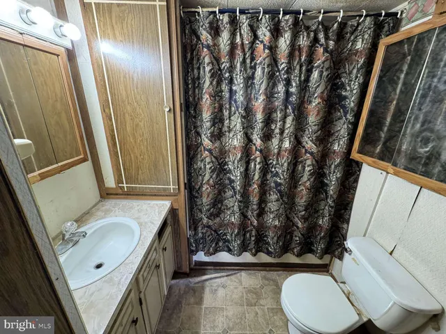 a bathroom with a granite countertop sink toilet and shower curtain