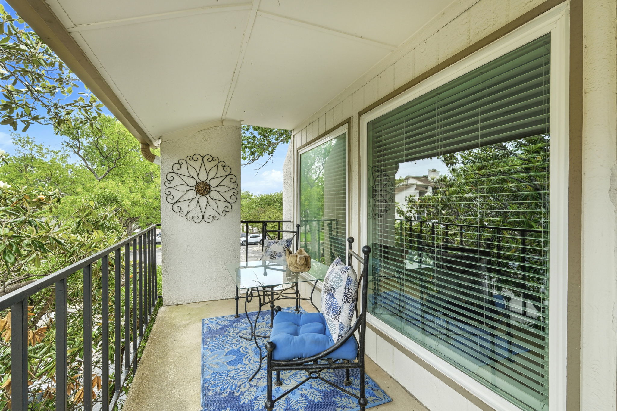 6910 Hart Lane, Unit 912 Austin, TX 78731 - Photo 2 of 36 Covered balcony featuring a concrete floor, dark metal railings, and a stucco exterior wall