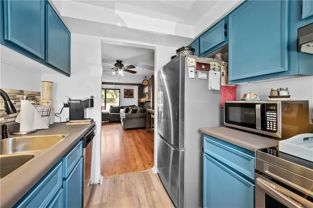 a kitchen with stainless steel appliances granite countertop a refrigerator a stove and a sink with wooden floors