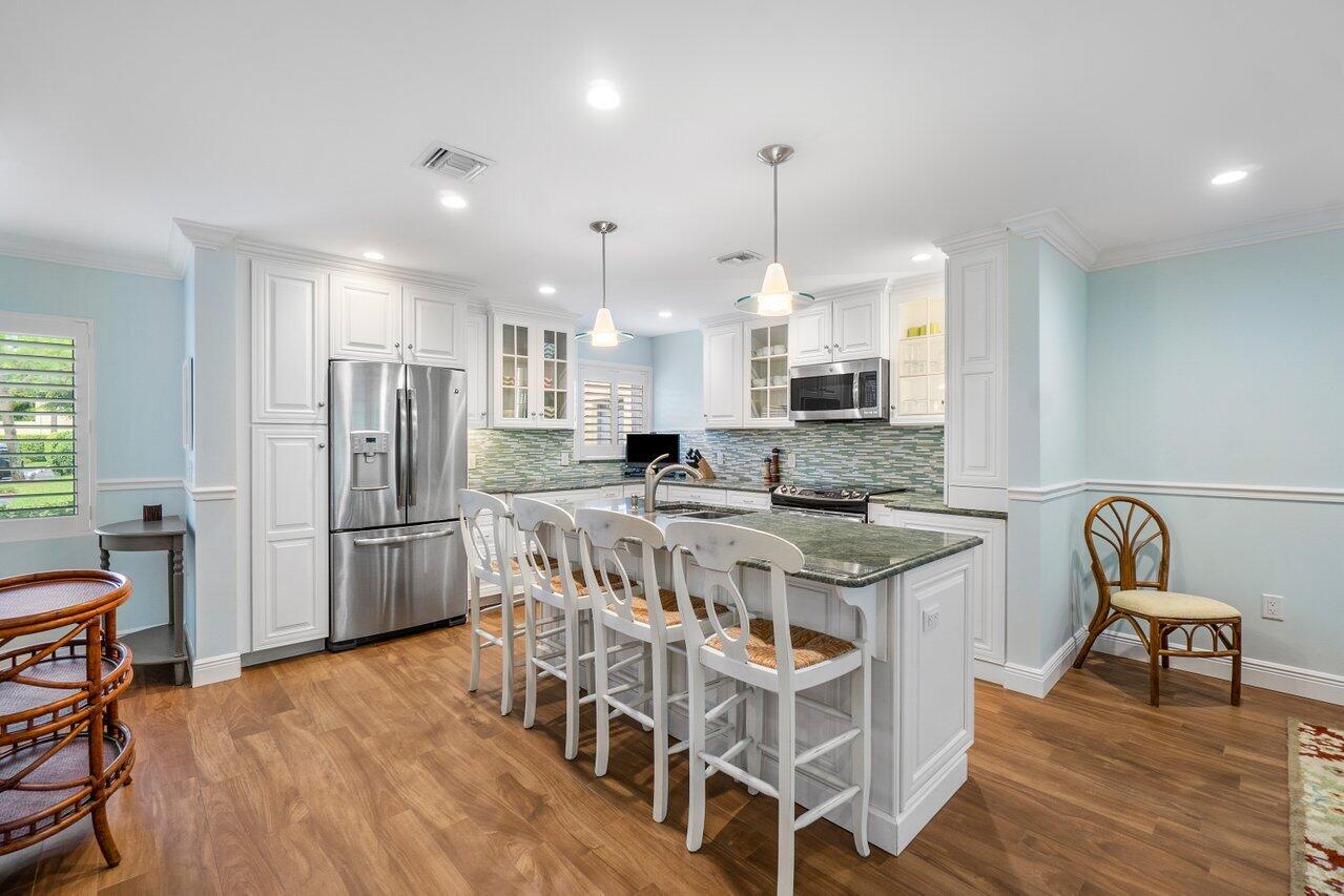 a kitchen with stainless steel appliances a stove a sink a refrigerator and a dining table