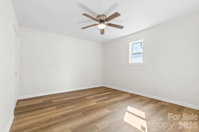 an empty room with wooden floor and ceiling fan