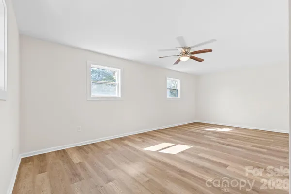 an empty room with a window and a fan