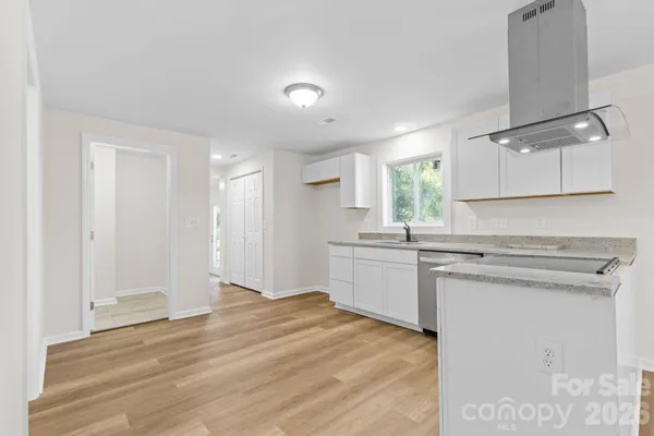 a kitchen with granite countertop a sink cabinets and wooden floor