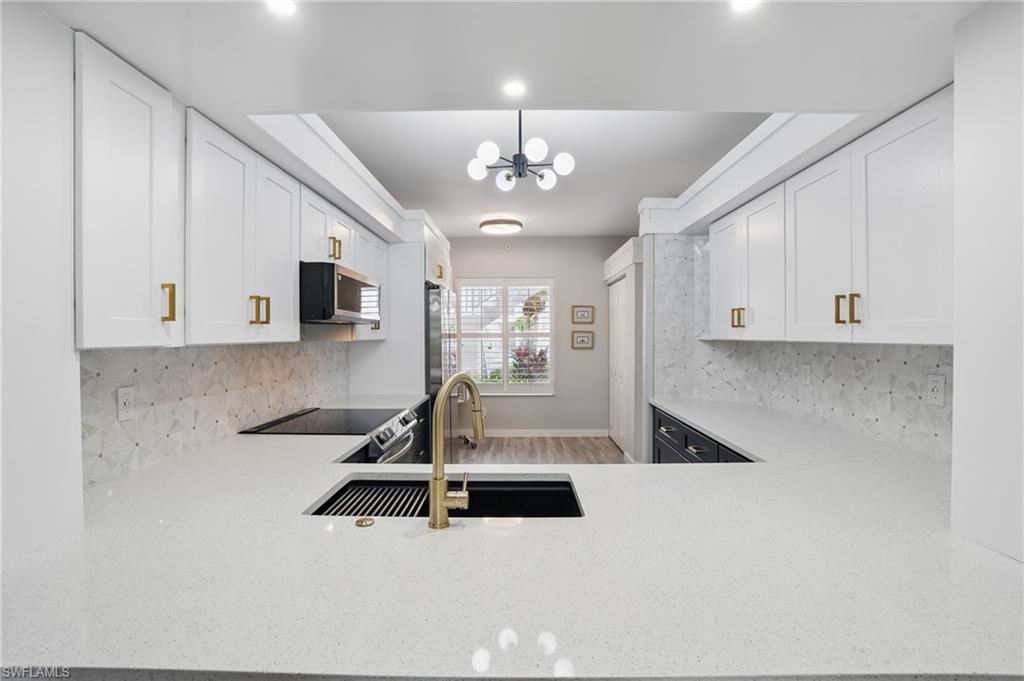 1220 Sarah Jean Circle, Unit L103 Naples, FL 34110 - Photo 11 of 50 Kitchen featuring stainless steel microwave, a sink, backsplash, and a chandelier