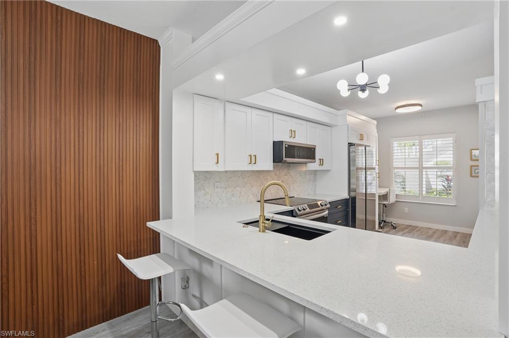 1220 Sarah Jean Circle, Unit L103 Naples, FL 34110 - Photo 12 of 50 a kitchen with stainless steel appliances a table and chairs in it