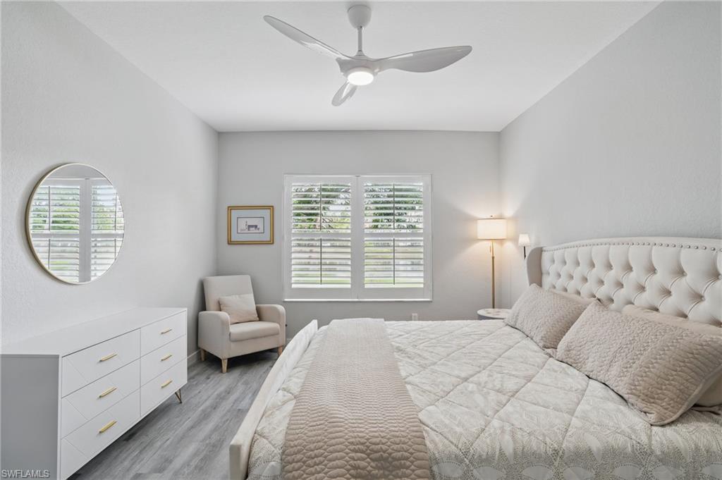 1220 Sarah Jean Circle, Unit L103 Naples, FL 34110 - Photo 19 of 50 a spacious bedroom with a bed a chandelier and a window