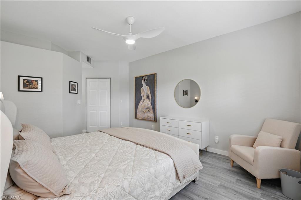 1220 Sarah Jean Circle, Unit L103 Naples, FL 34110 - Photo 20 of 50 Bedroom featuring light wood-style floors, a closet, a ceiling fan, and baseboards