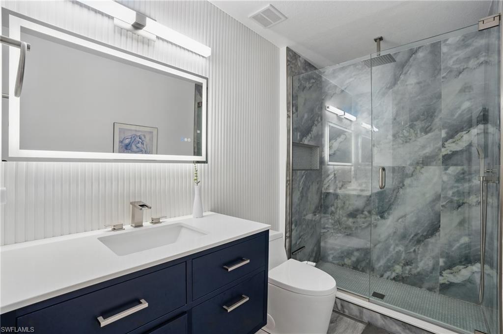 1220 Sarah Jean Circle, Unit L103 Naples, FL 34110 - Photo 26 of 50 a bathroom with a sink a toilet a mirror and a shower