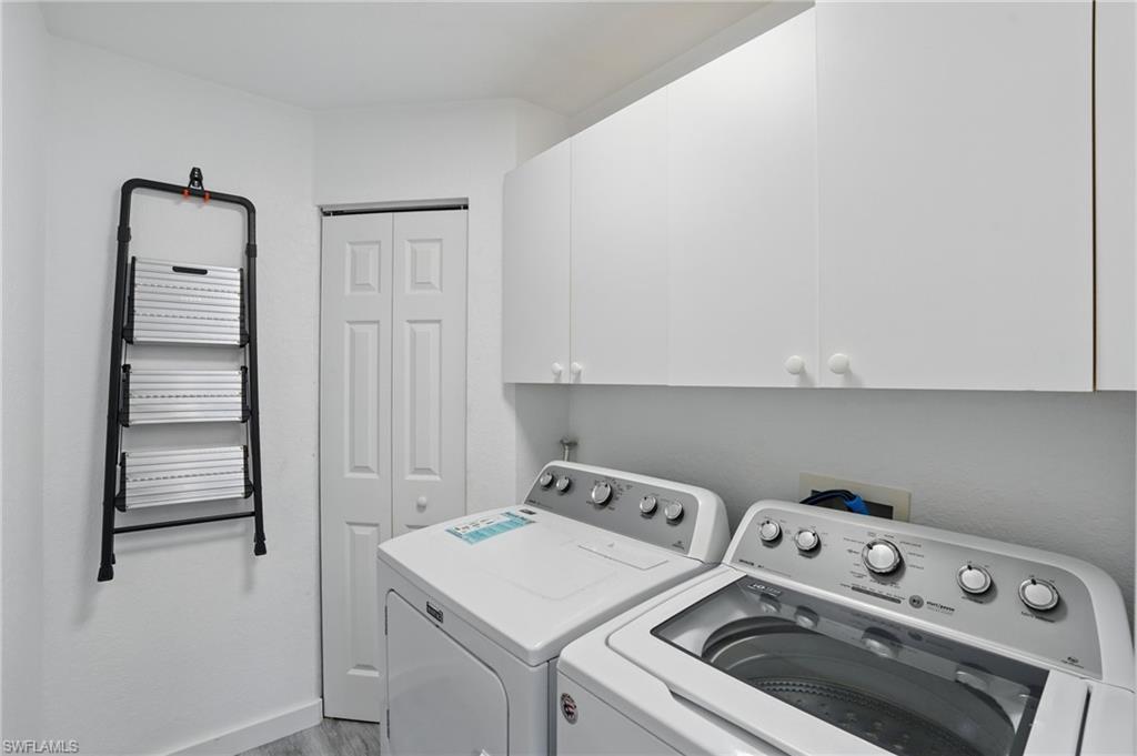 1220 Sarah Jean Circle, Unit L103 Naples, FL 34110 - Photo 28 of 50 Clothes washing area with washing machine and clothes dryer, cabinet space, and wood finished floors