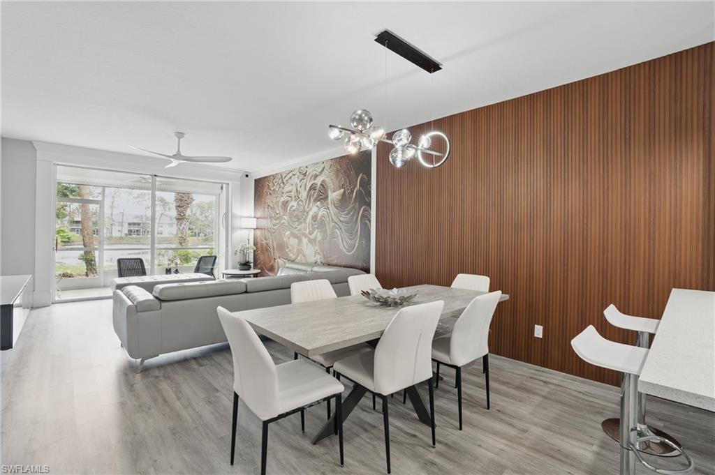 1220 Sarah Jean Circle, Unit L103 Naples, FL 34110 - Photo 6 of 50 Dining space with light wood-style flooring, ceiling fan, wooden walls, and a chandelier