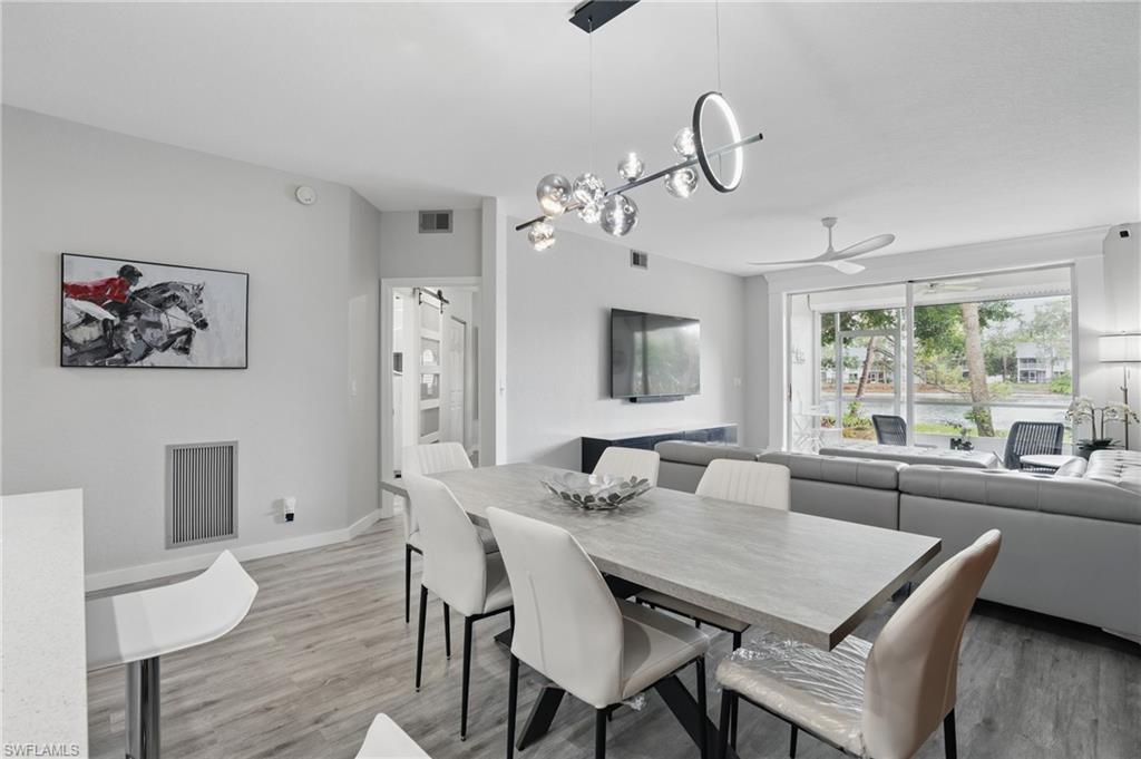 1220 Sarah Jean Circle, Unit L103 Naples, FL 34110 - Photo 7 of 50 Dining space featuring a ceiling fan, light wood-style flooring, baseboards, and a chandelier