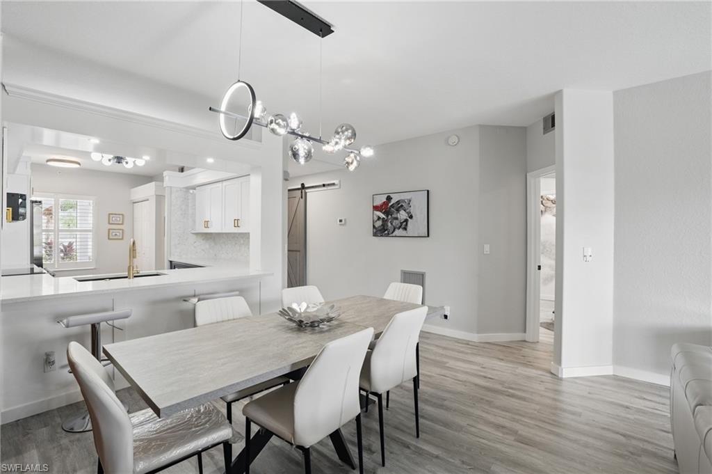 1220 Sarah Jean Circle, Unit L103 Naples, FL 34110 - Photo 9 of 50 Dining area featuring a barn door, light wood-style floors, and baseboards