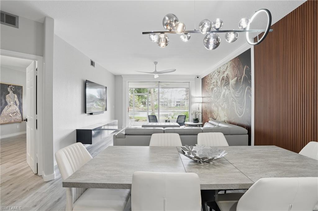 1220 Sarah Jean Circle, Unit L103 Naples, FL 34110 - Photo 10 of 50 Dining room with a ceiling fan, light wood-type flooring, baseboards, and a chandelier