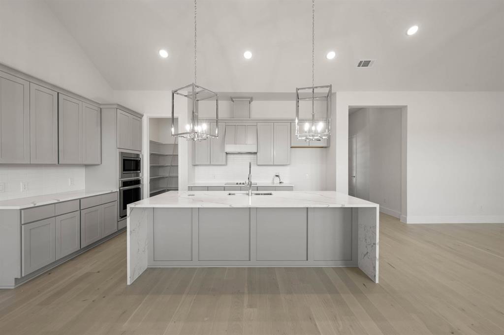 141 Olson Road Waxahachie, TX 75165 - Photo 22 of 24 a large white kitchen with a sink and dishwasher a stove top oven with wooden floor
