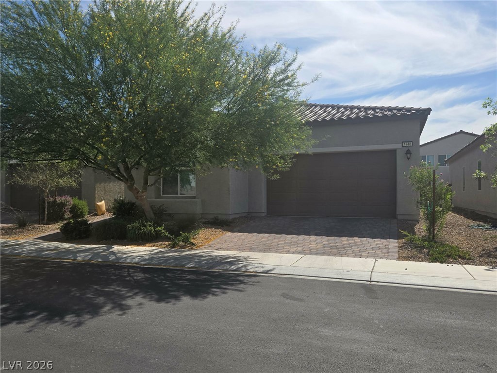 4748 Ritual Street North Las Vegas, NV 89031 - Photo 2 of 31 A single-story home with a two-car garage features a desert-friendly front yard and paved driveway.