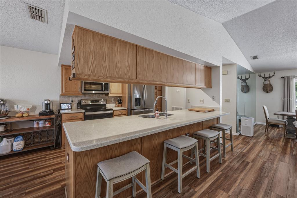 7435 Kilbride Court Weeki Wachee, FL 34613 - Photo 15 of 67 a kitchen with stainless steel appliances a table chairs stove and refrigerator