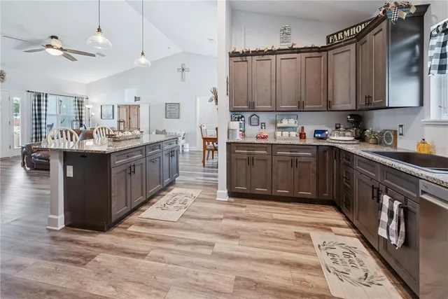 a kitchen with stainless steel appliances granite countertop a stove top oven a sink dishwasher and cabinets with wooden floor