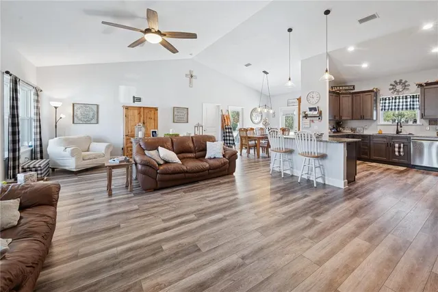 a living room with furniture kitchen view and a wooden floor