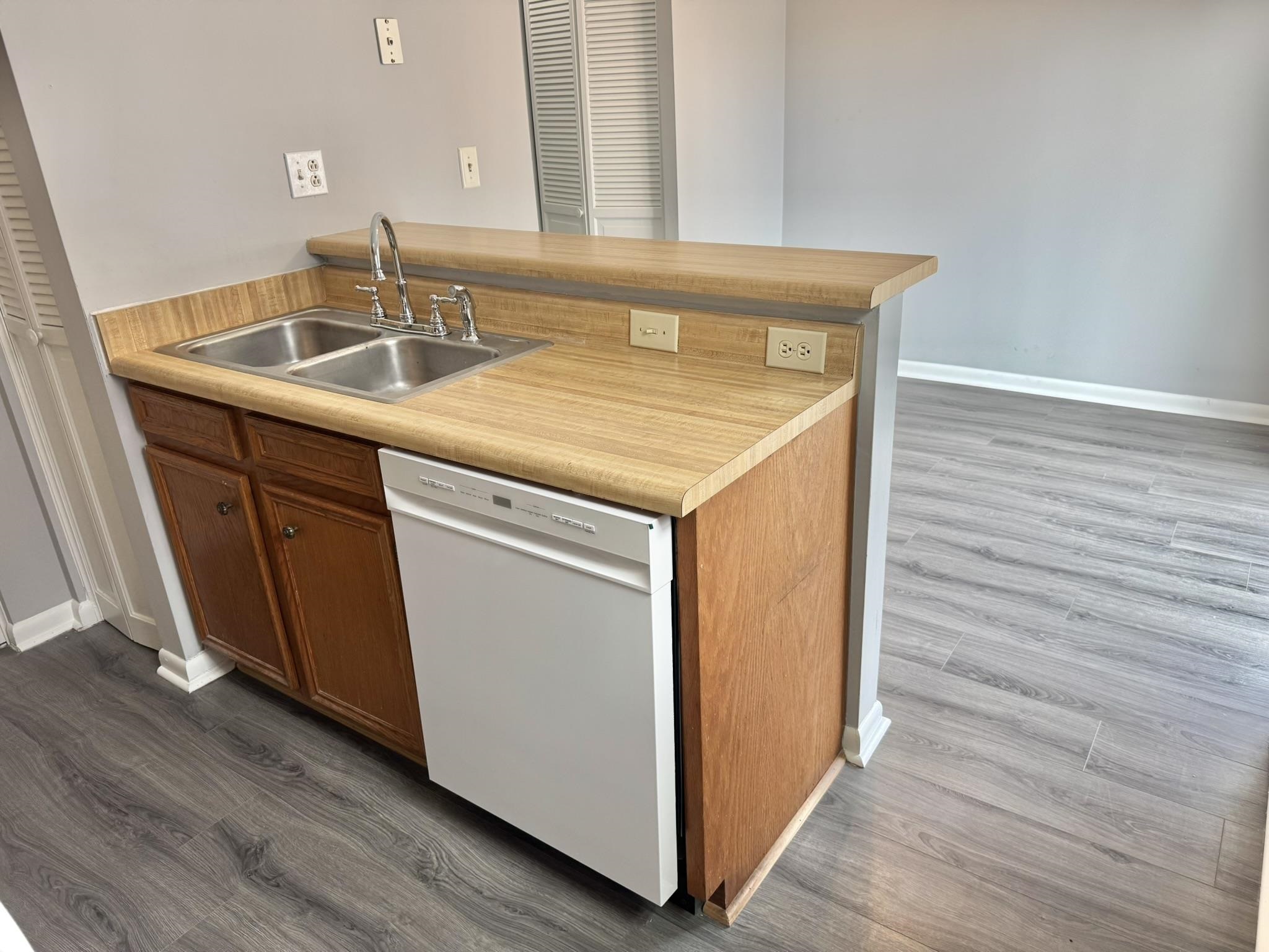 4115 Little River Road, Unit 10B Myrtle Beach, SC 29577 - Photo 12 of 31 Kitchen featuring dark wood-type flooring, brown cabinets, light countertops, white dishwasher, and a peninsula