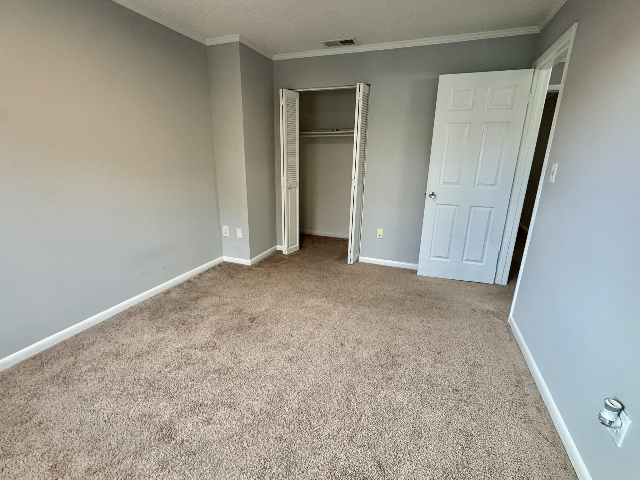 4115 Little River Road, Unit 10B Myrtle Beach, SC 29577 - Photo 23 of 31 Unfurnished bedroom featuring a closet, carpet, crown molding, and a textured ceiling