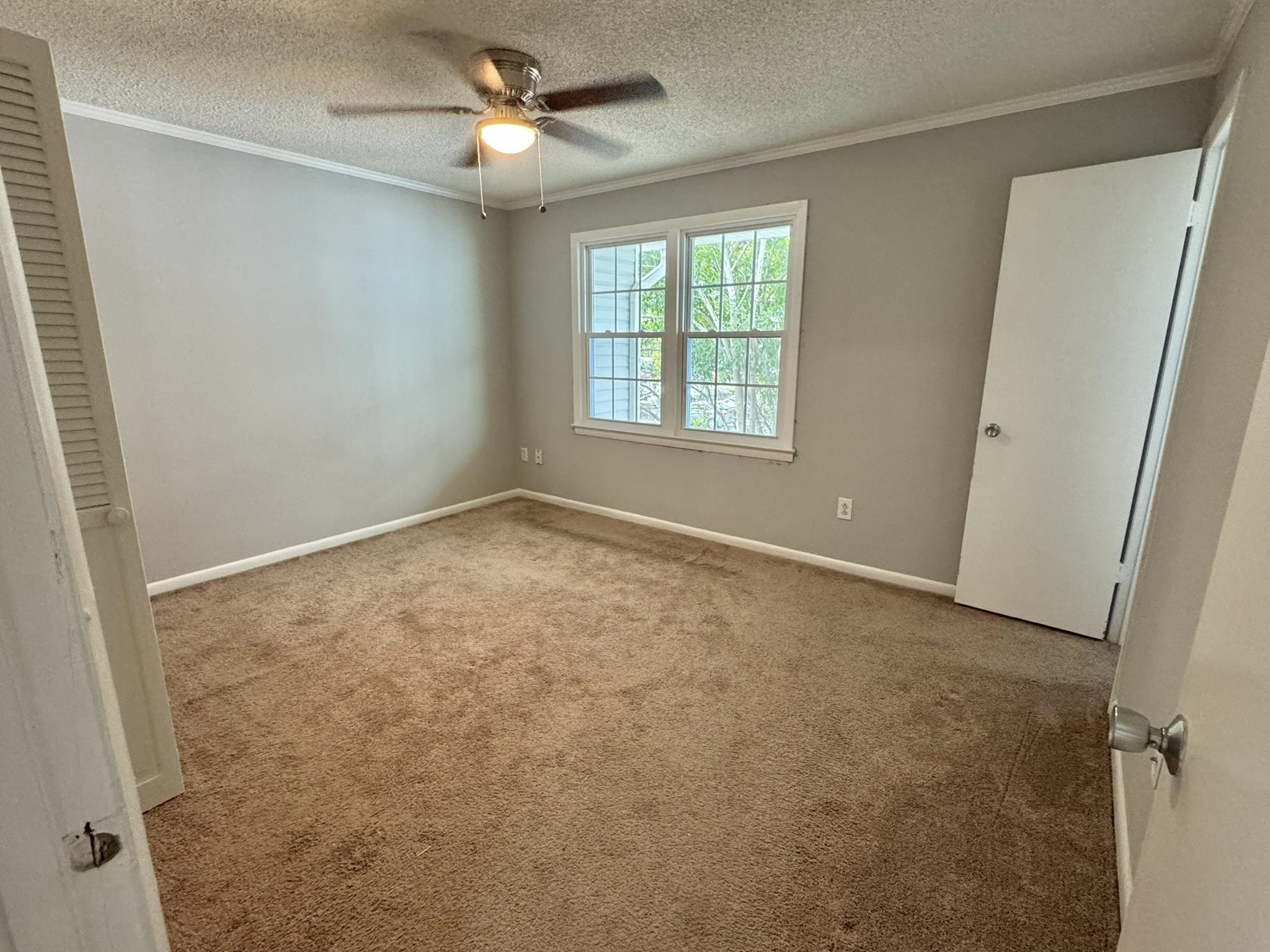 4115 Little River Road, Unit 10B Myrtle Beach, SC 29577 - Photo 28 of 31 Unfurnished bedroom with carpet floors, crown molding, a textured ceiling, and a ceiling fan