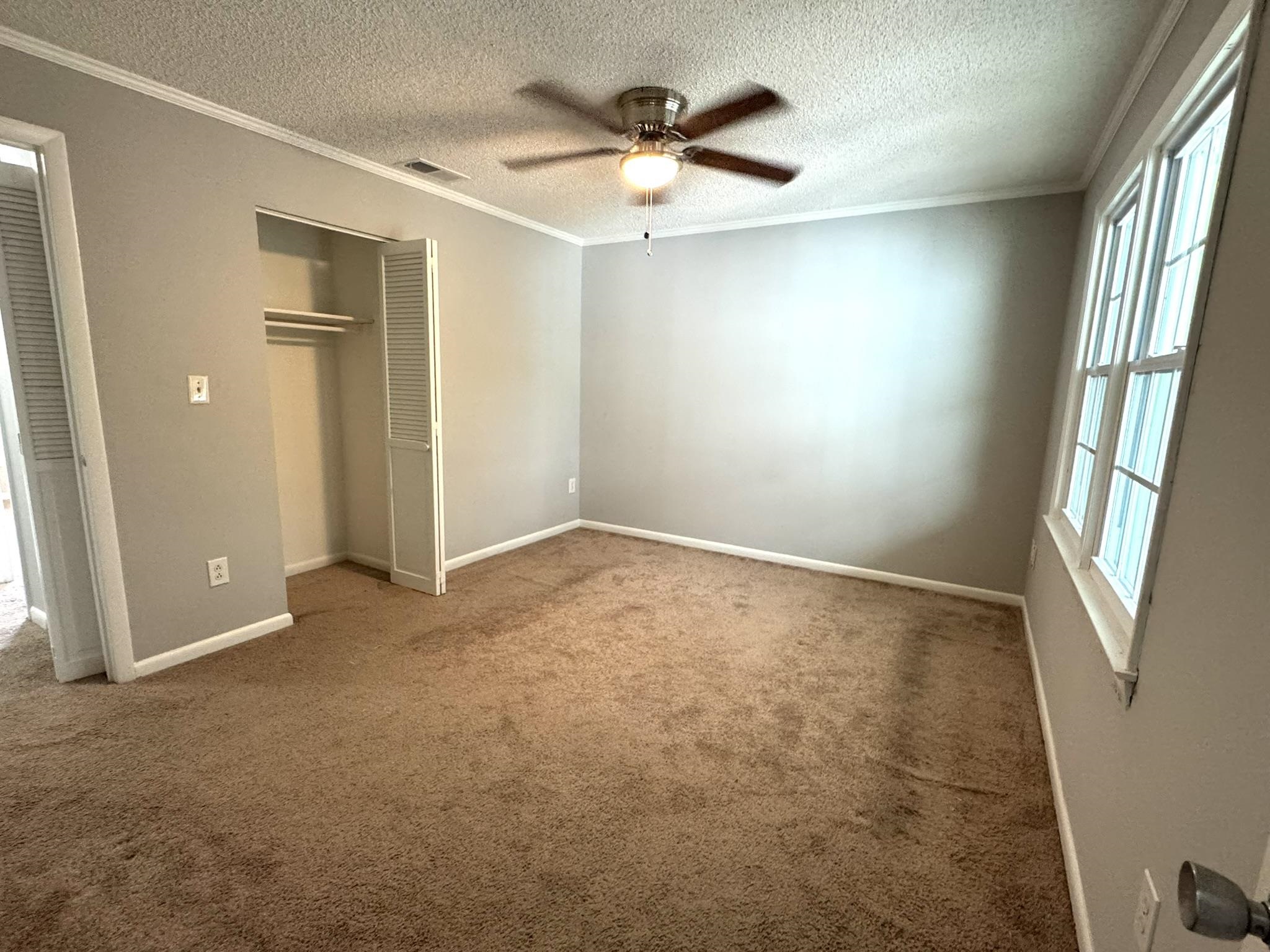 4115 Little River Road, Unit 10B Myrtle Beach, SC 29577 - Photo 29 of 31 Unfurnished bedroom with crown molding, a closet, a textured ceiling, a ceiling fan, and carpet