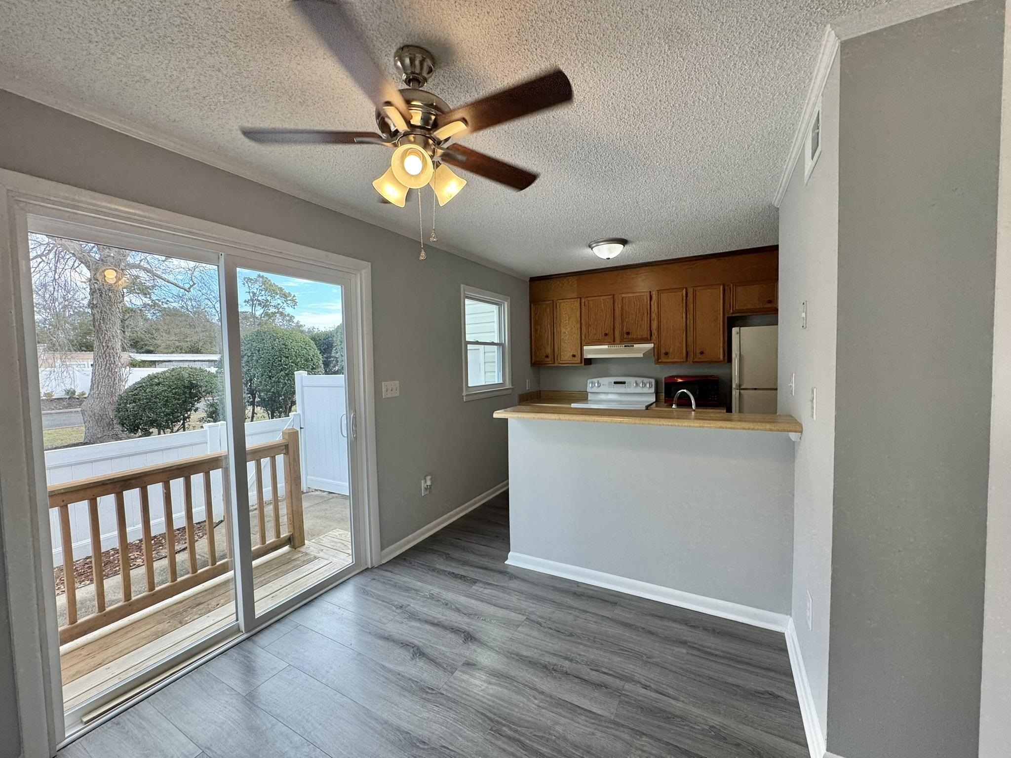 4115 Little River Road, Unit 10B Myrtle Beach, SC 29577 - Photo 9 of 31 Kitchen featuring brown cabinetry, light countertops, dark wood-style floors, white appliances, and ceiling fan