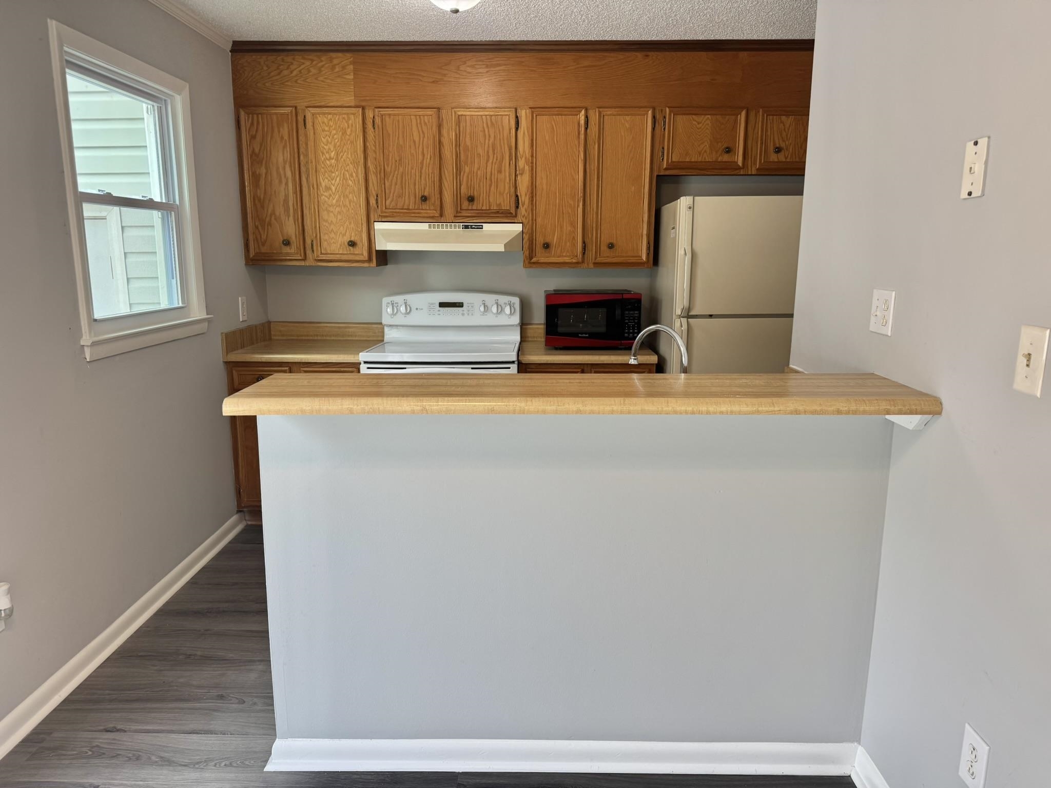 4115 Little River Road, Unit 10B Myrtle Beach, SC 29577 - Photo 10 of 31 Kitchen with light countertops, white appliances, brown cabinets, a peninsula, and a textured ceiling