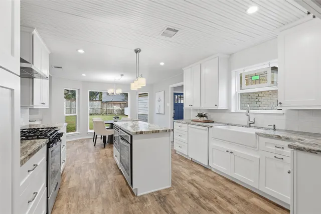 a kitchen with counter top space a sink wooden floor and stainless steel appliances