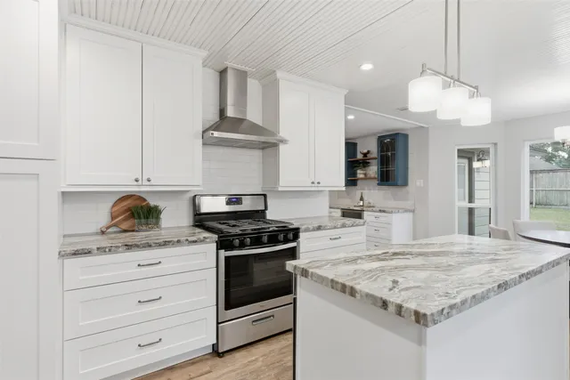 a kitchen with granite countertop stainless steel appliances a stove cabinets and wooden floor