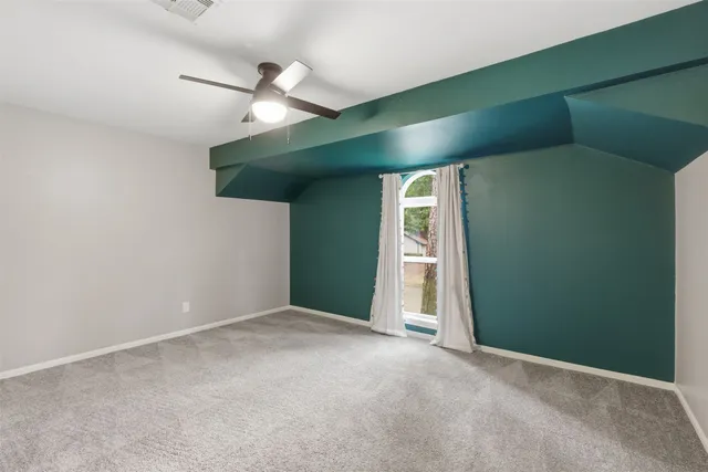 an empty room with a ceiling fan and carpet