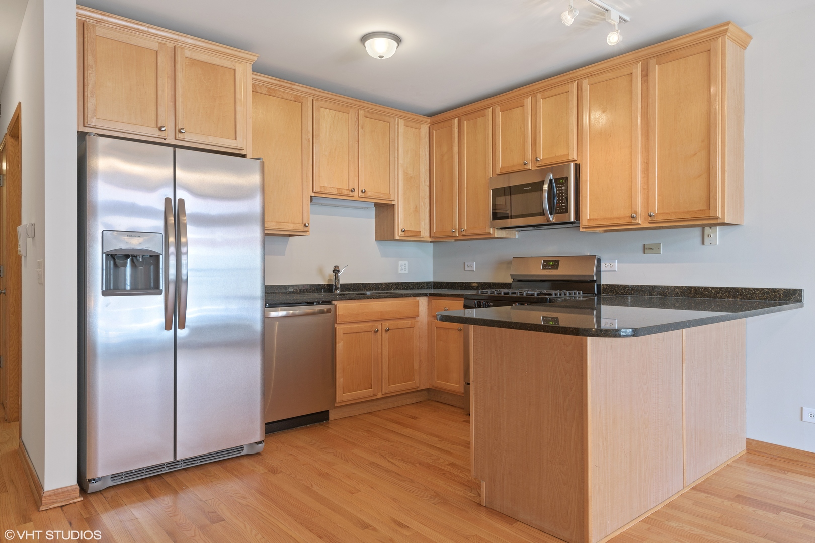 927 North Noble Street, Unit 1 Chicago, IL 60642 - Photo 4 of 10 a kitchen with stainless steel appliances granite countertop a refrigerator a sink a stove a microwave and cabinets