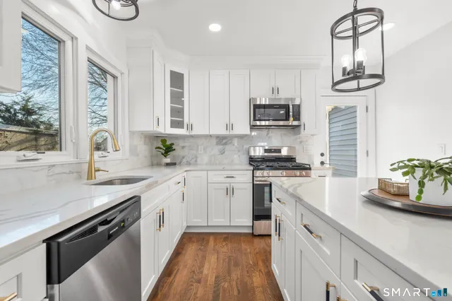 a kitchen with cabinets stainless steel appliances a sink and a stove
