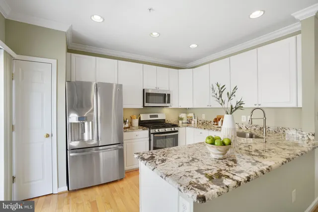 a kitchen with granite countertop a refrigerator a stove a sink a counter space and cabinets