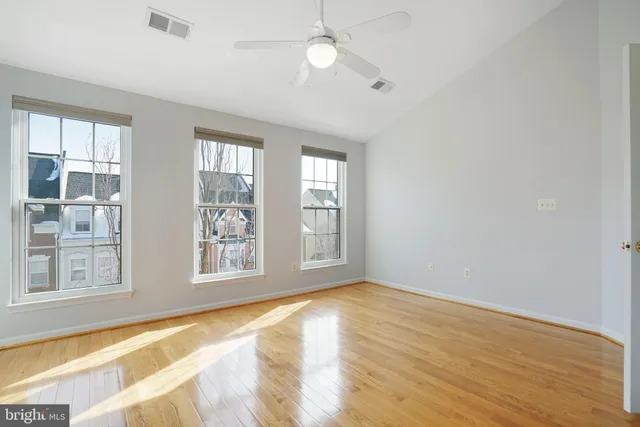 a view of an empty room with window and wooden floor