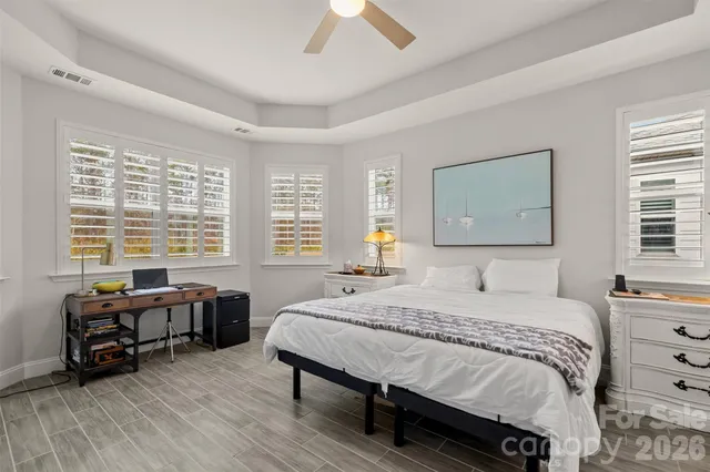 a bedroom with a bed a large window and a chandelier