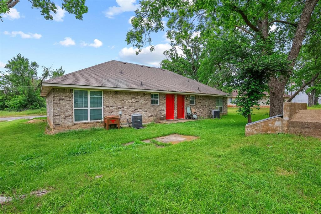 704 Seven Oaks Road Bonham, TX 75418 - Photo 2 of 11 Brick exterior building featuring red entry doors and a brown shingle roof