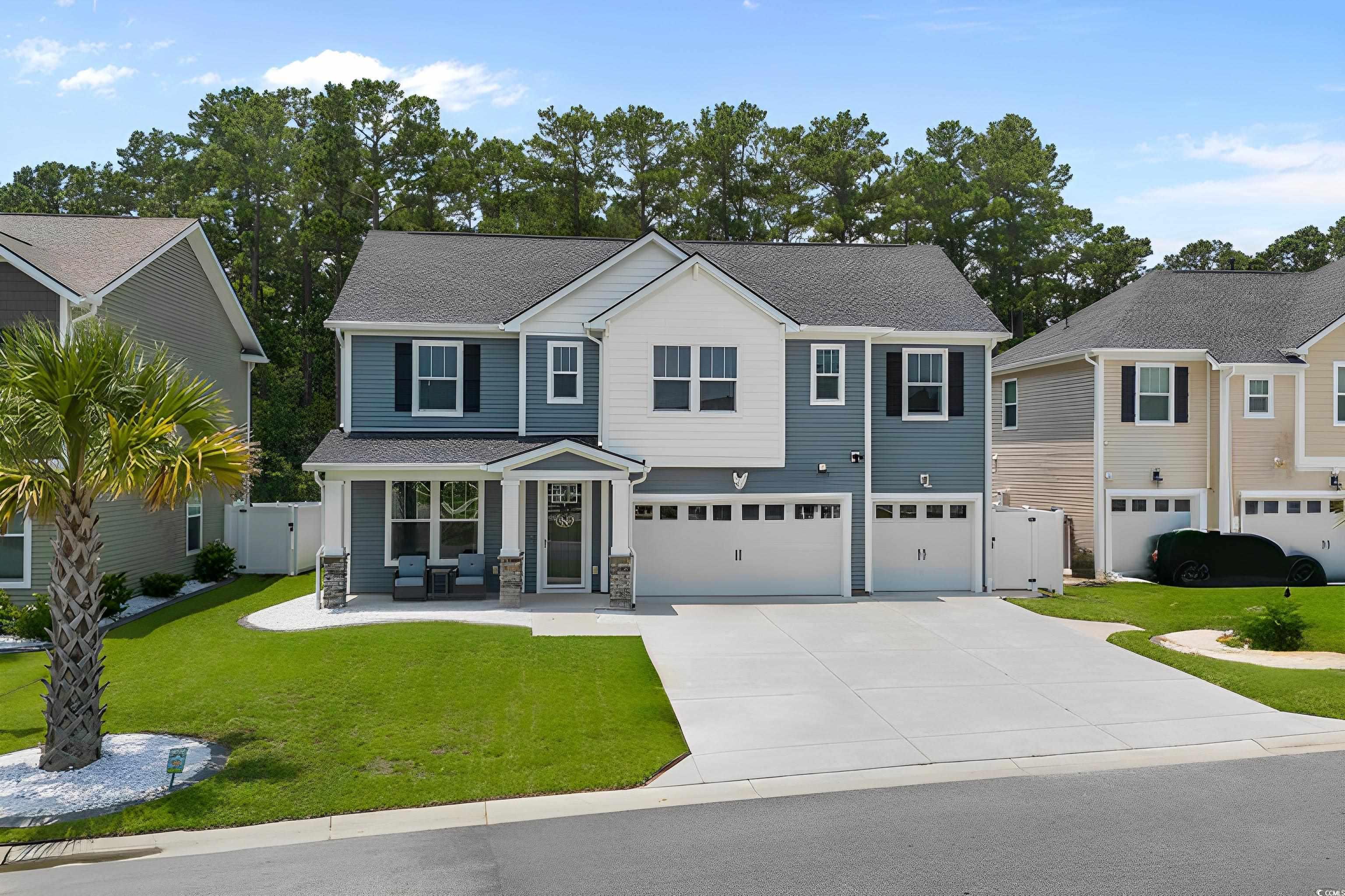 View of front facade featuring an attached garage, concrete driveway, a gate, stone siding, and roof with shingles