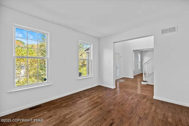 a view of an empty room with wooden floor and stairs