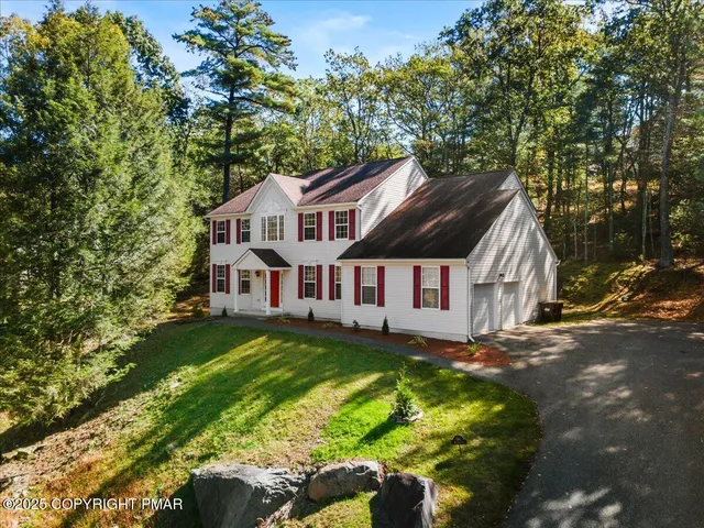 a view of a house with a big yard plants and large trees