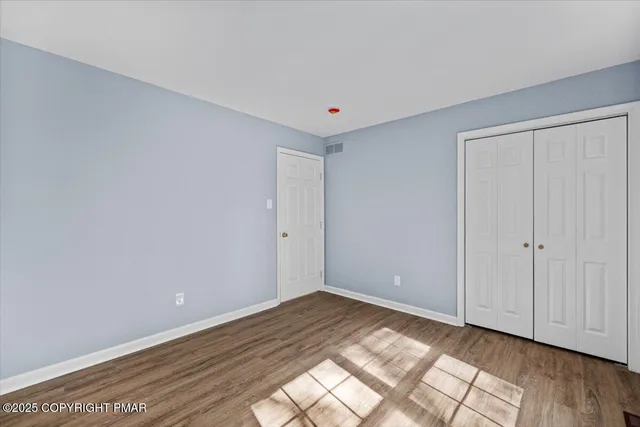 a view of an empty room with window and wooden floor