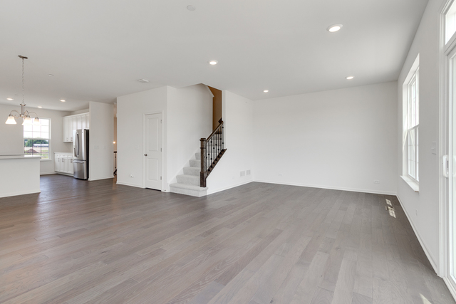 1627 Sager Way Batavia, IL 60510 - Photo 12 of 25 an empty room with wooden floor and a kitchen