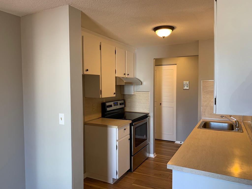 96 Main Street, Unit C4 Foxboro, MA 02035 - Photo 7 of 14 a kitchen with stainless steel appliances granite countertop a refrigerator a stove and a sink with wooden floor