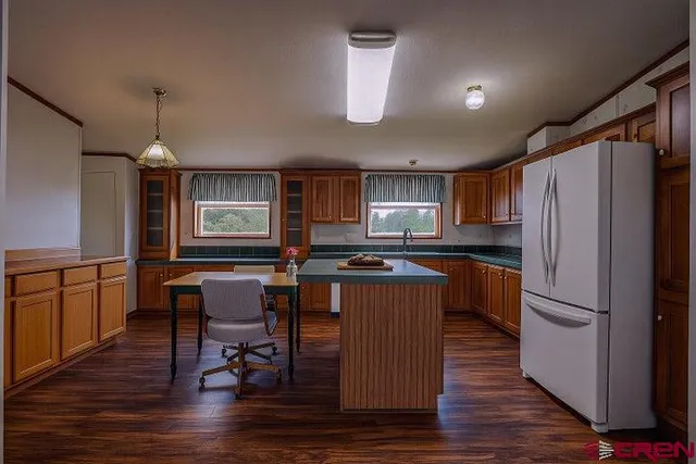 a kitchen with stainless steel appliances granite countertop a refrigerator a sink dishwasher a stove and a dining table with wooden floor