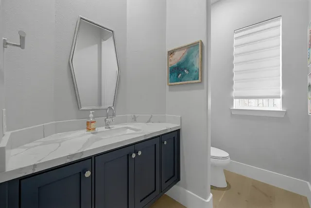 a bathroom with a granite countertop toilet a sink and a mirror