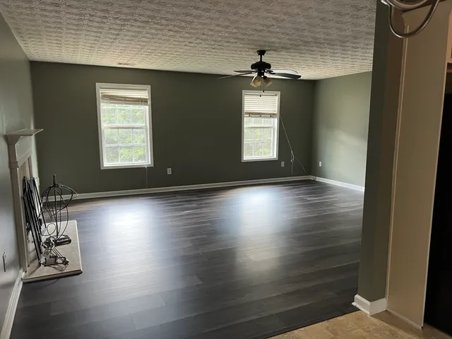 a view of an empty room with window and wooden floor