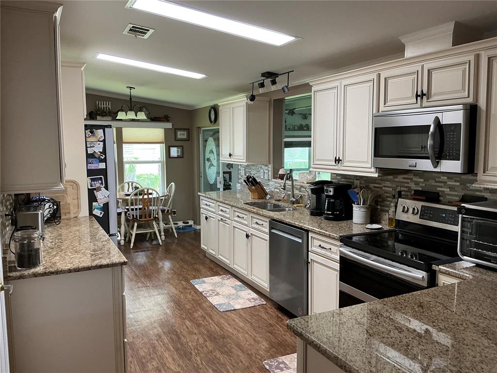236 Allies Pass, Unit 363 Frostproof, FL 33843 - Photo 14 of 51 a kitchen with stainless steel appliances granite countertop a stove top oven a sink dishwasher a dining table and chairs with wooden floor