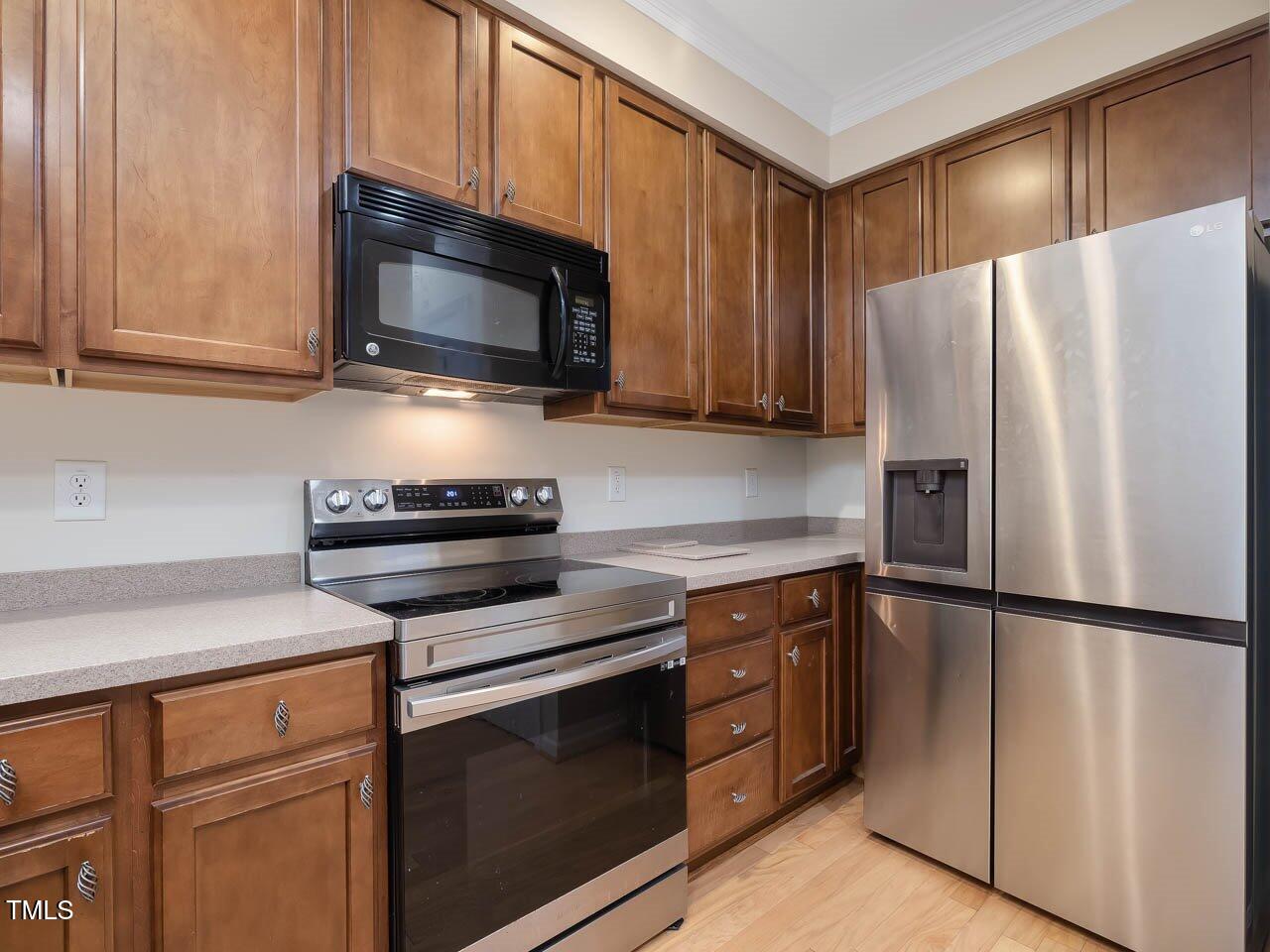 4719 Altha Street Raleigh, NC 27606 - Photo 4 of 19 a kitchen with stainless steel appliances wooden cabinets and a stove top oven