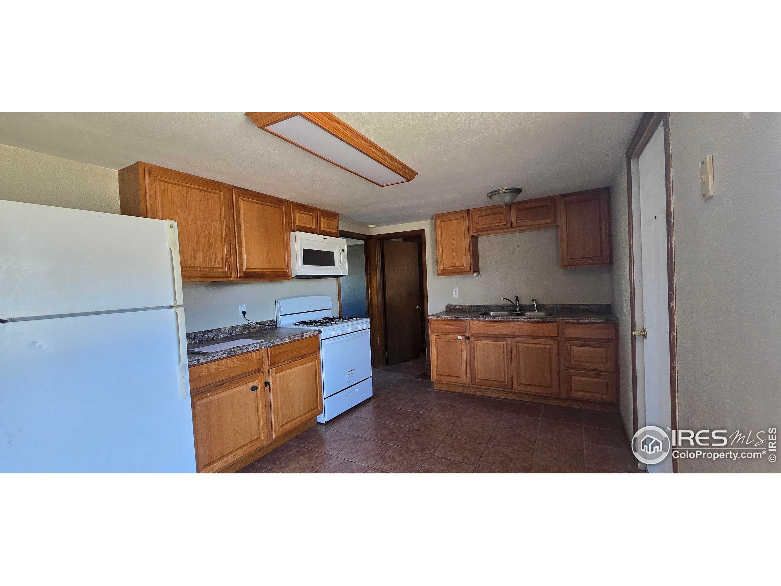 312 Main Street Wiggins, CO 80654 - Photo 3 of 8 a kitchen with granite countertop a refrigerator stove top oven and sink