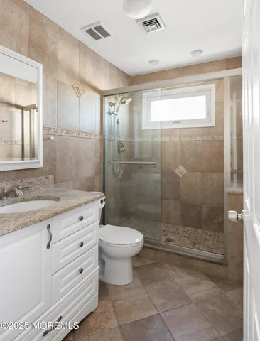 a bathroom with a granite countertop sink a toilet and shower